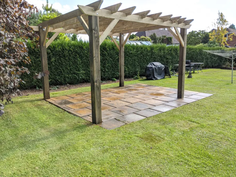Timber pergola built over a sandstone paved seating area set into a lawn